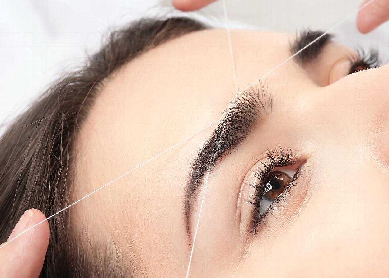 Woman having brow threading procedure done